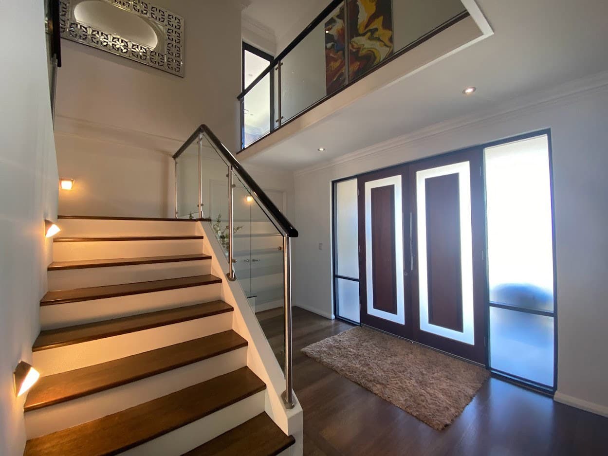 Freshly painted entry with timber stairs, glass balustrade and double front doors
