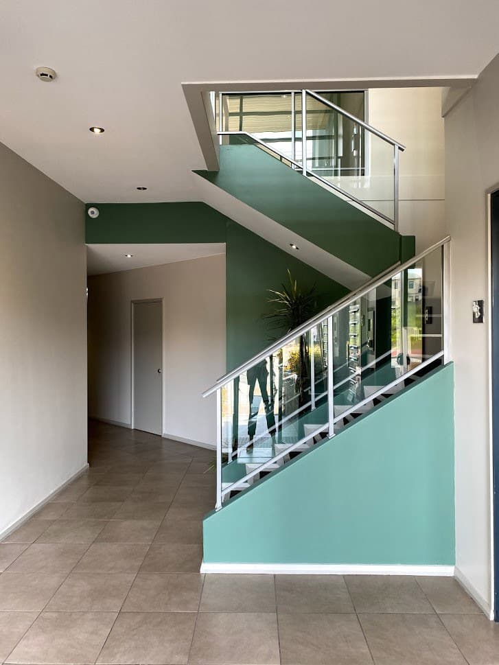 Commercial stairwell painted white, green and mint with a glass balustrade
