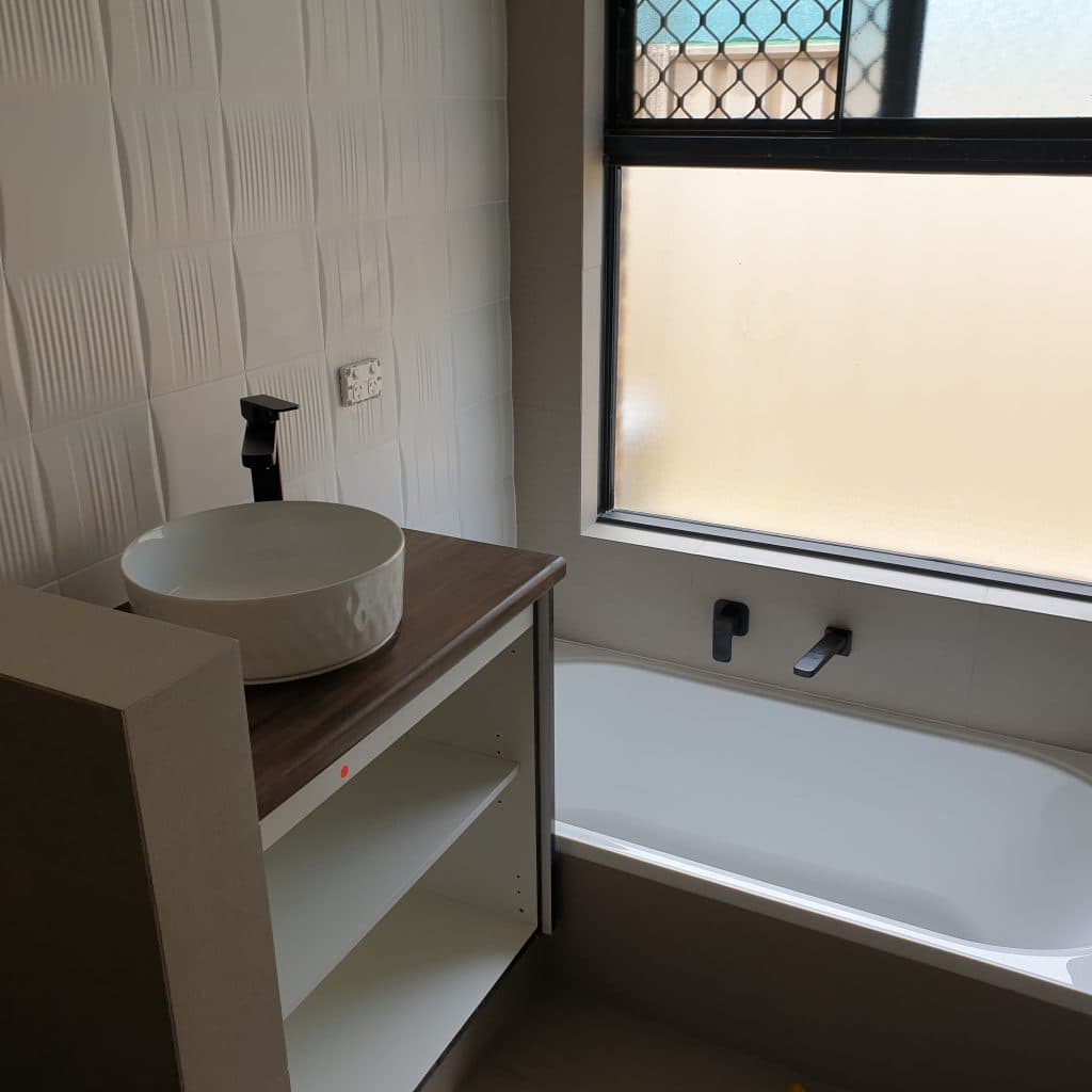 New bathroom with a vessel basin, timber vanity top, and bath with black tapware