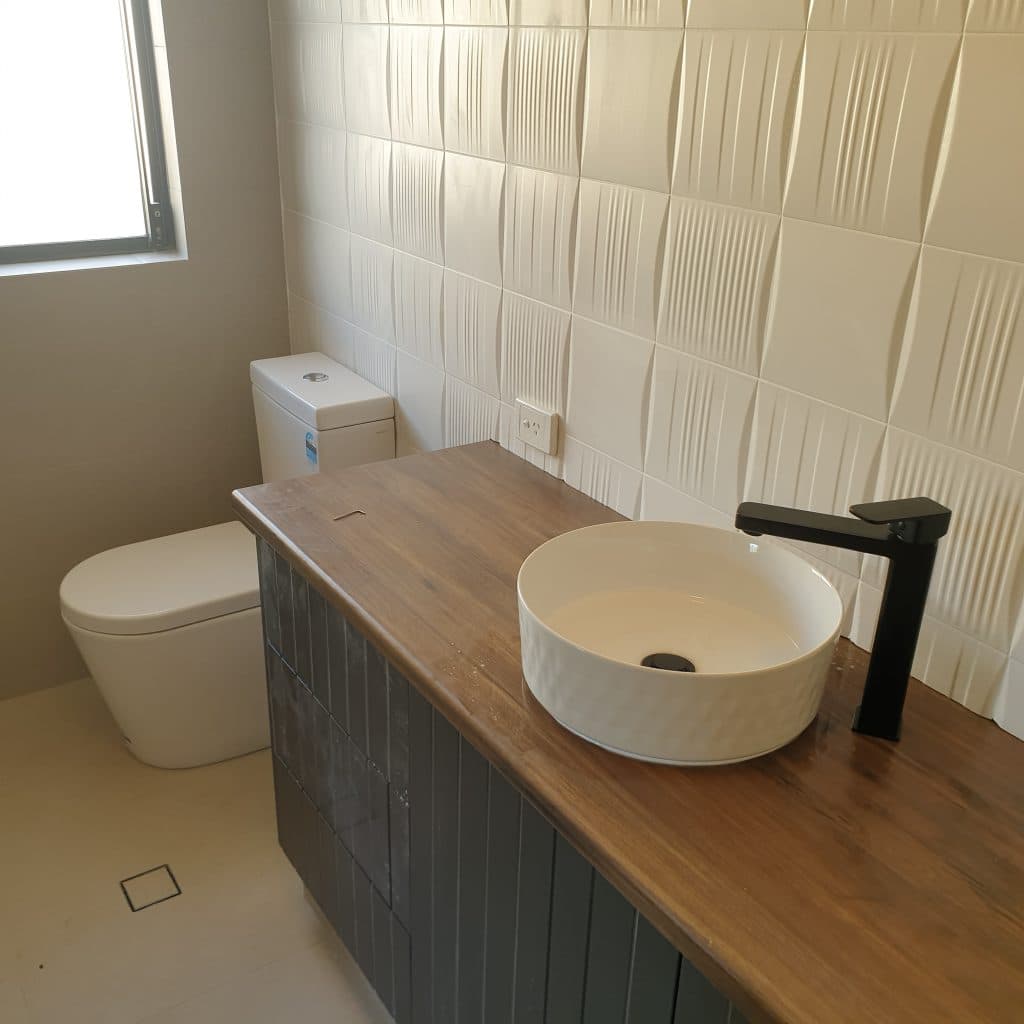 Toilet and timber vanity with a white vessel basin and black mixer