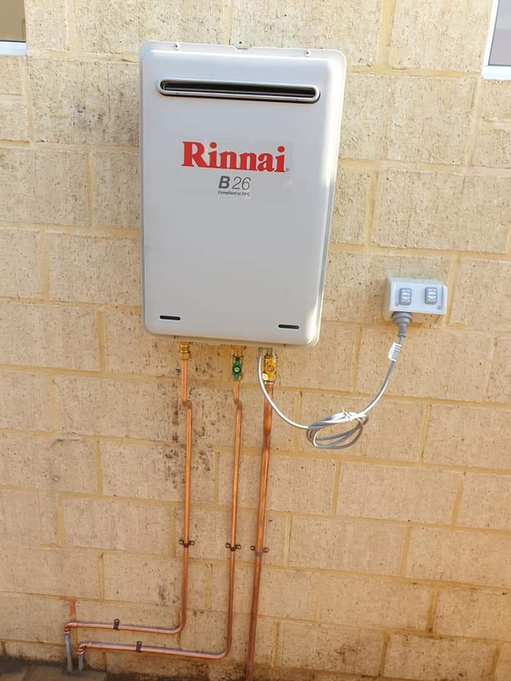 Rinnai continuous-flow hot water unit on a cream brick wall with copper pipework
