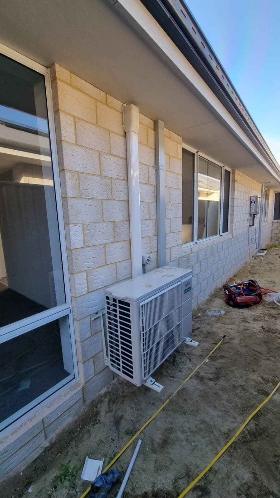 Outdoor air-conditioning unit on a limestone wall with new conduit