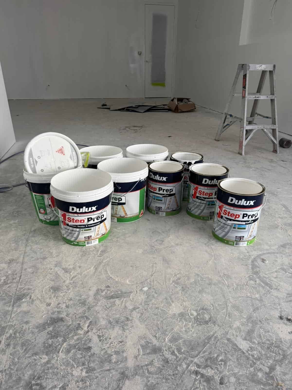 Dulux Step Prep tins on a concrete floor in an empty room ready to paint