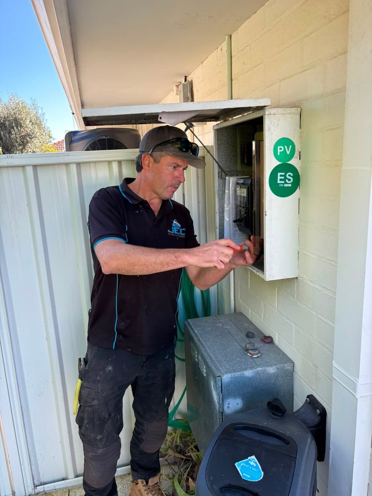 Glen in a JEC shirt working at an outdoor switchboard
