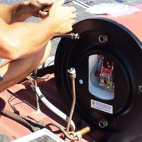 Plumber working on a rooftop solar hot water cylinder