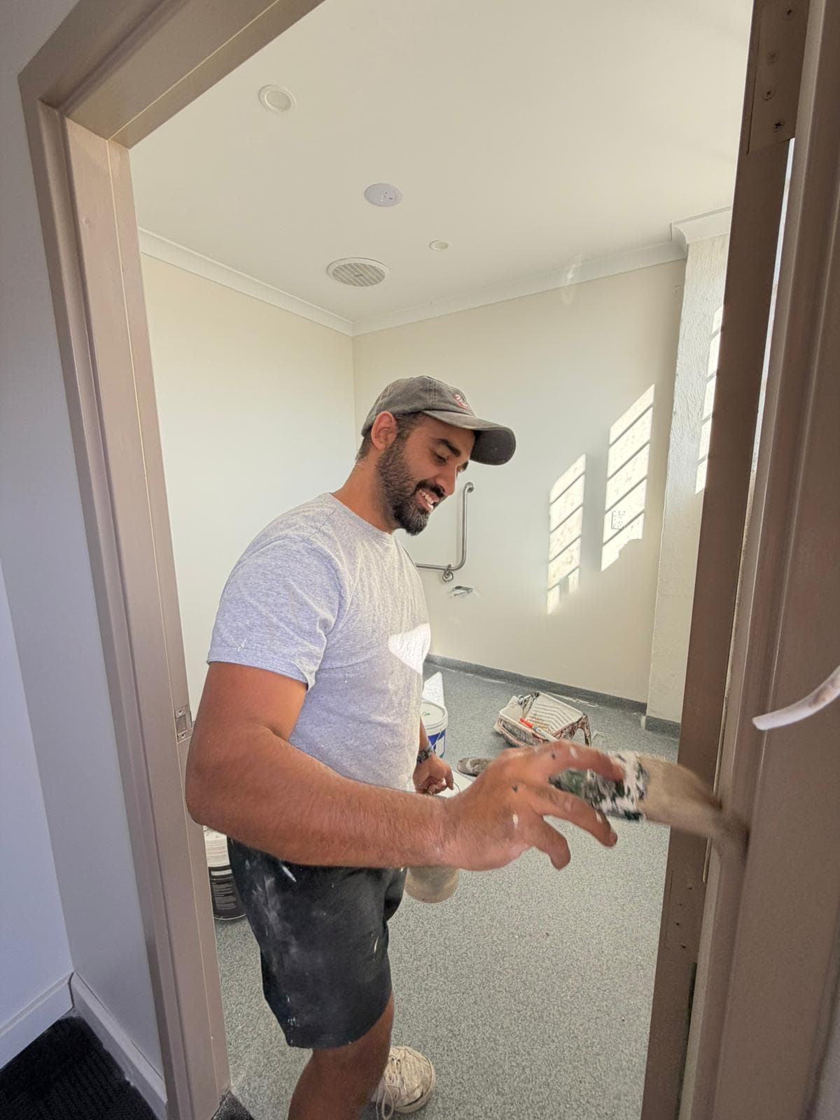 Daniel of Timeless Tints painting a door frame with a brush and paint pot